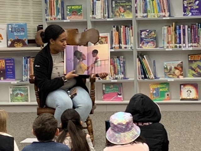 A picture of a woman reading a book to children.
